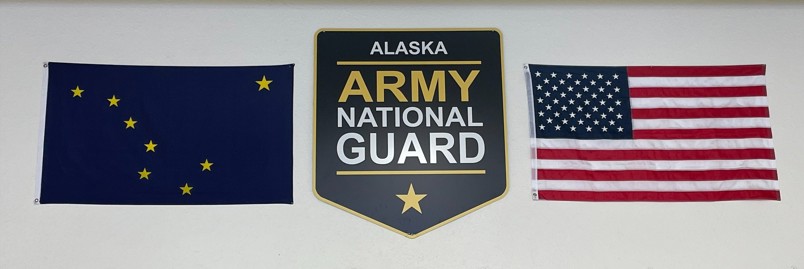 Picture, from left to right, of the Alaska State flag, Alaska Army National Guard shield, and the United States Flag.